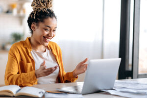 Online communication. Confident joyful beautiful african american young female student or freelancer with afro dreadlocks, study remotely, talks by online conference with coworkers or teacher, smile